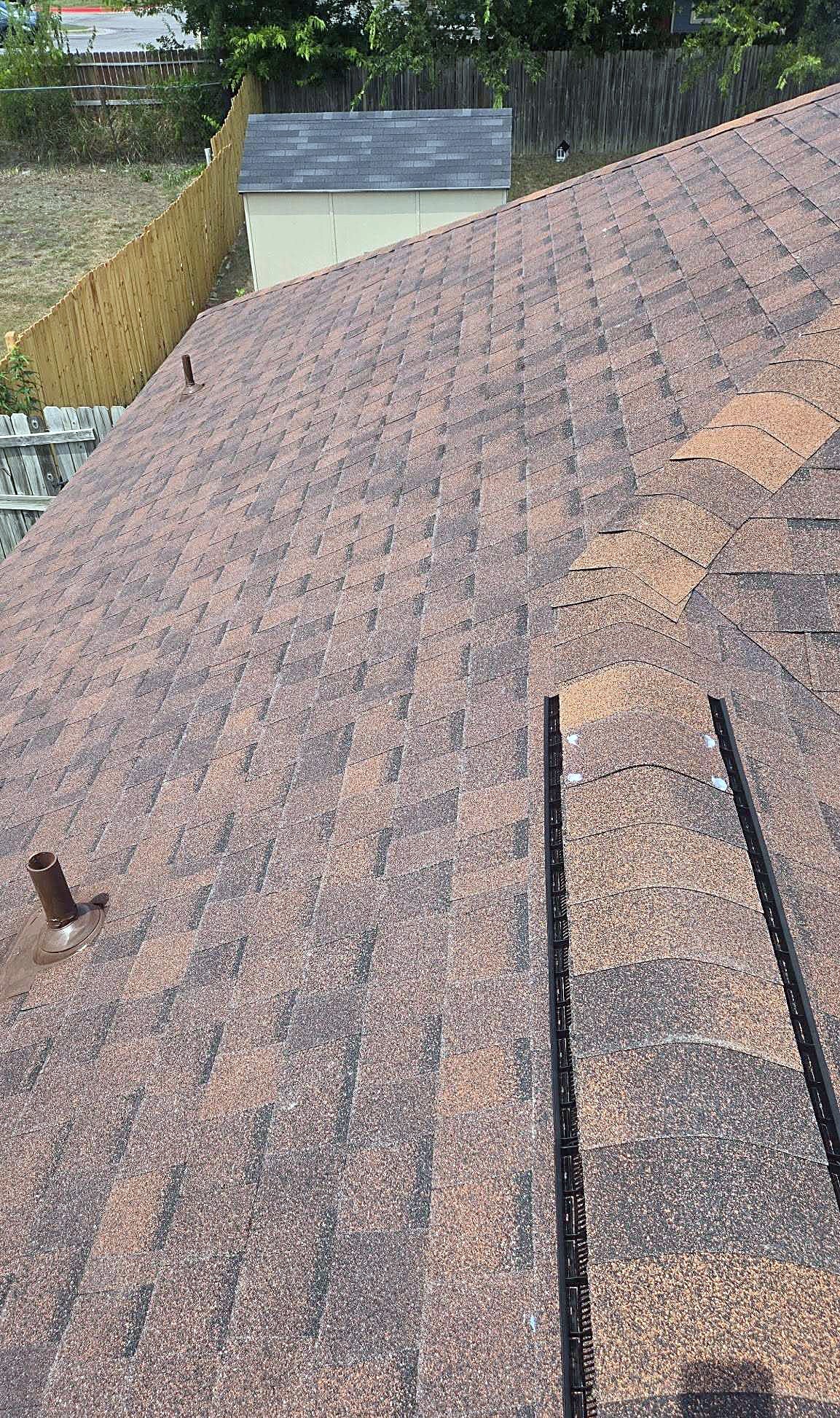 Close view of brown architectural shingles running up to a ridge cap
