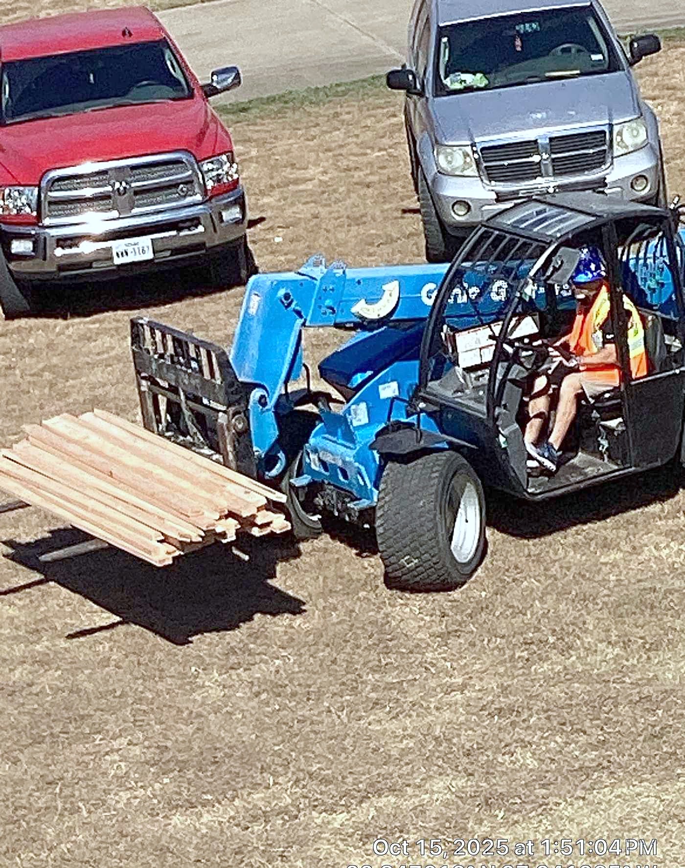 Two pickup trucks and a telehandler loaded with a bundle of lumber